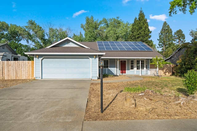 ranch-style house with fence, covered porch, concrete driveway, an attached garage, and solar panels