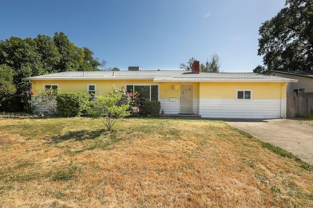 ranch-style home with stucco siding, a front lawn, fence, and a chimney