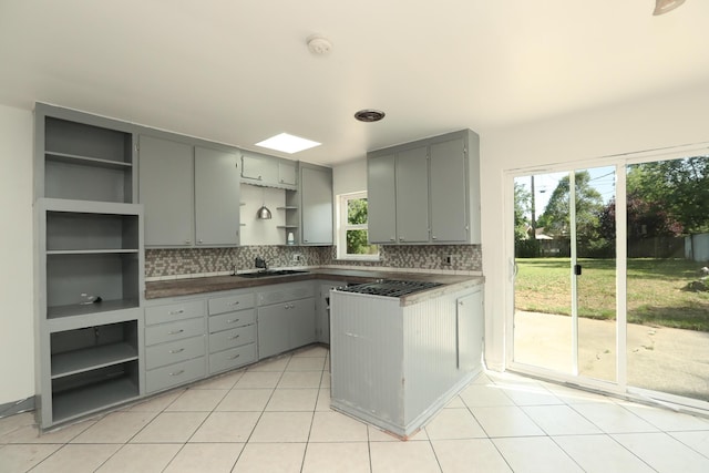 kitchen with open shelves, a sink, a peninsula, and gray cabinetry