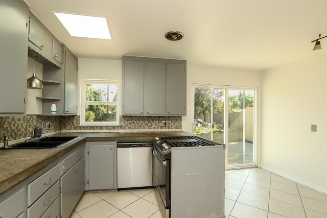 kitchen featuring stainless steel dishwasher, dark countertops, tasteful backsplash, gas stove, and gray cabinetry