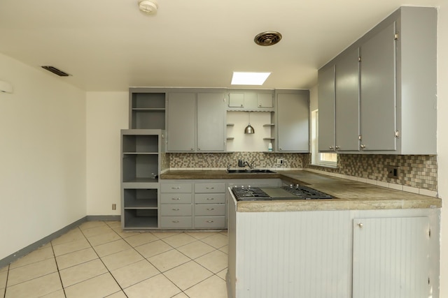 kitchen with open shelves, a sink, gray cabinets, and tasteful backsplash