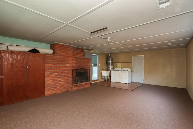 unfurnished living room featuring visible vents, a brick fireplace, a sink, water heater, and separate washer and dryer