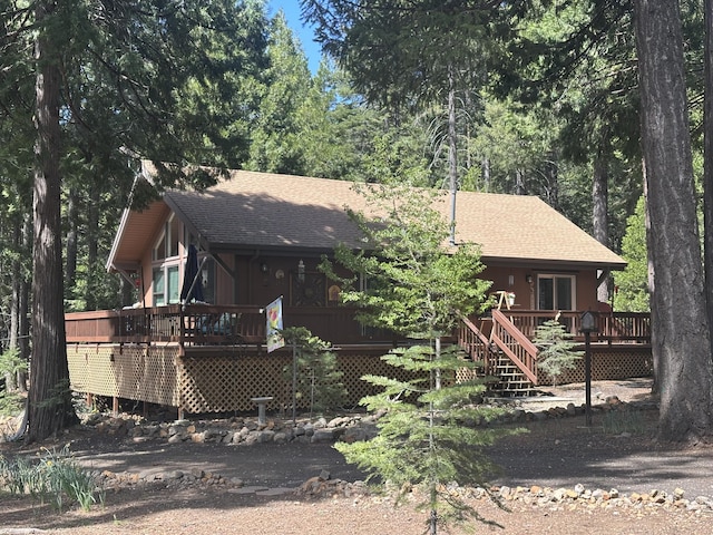 view of front of house with a shingled roof, a wooden deck, and stairway