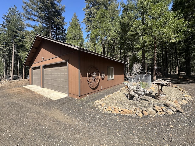 view of side of home with a detached garage and an outbuilding