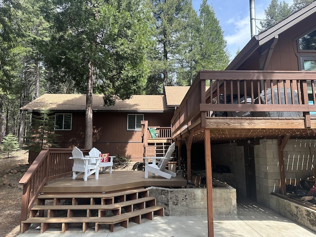 rear view of house featuring a shingled roof, a wooden deck, and stairs