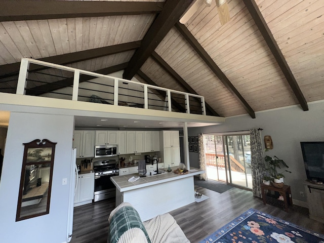 kitchen with tile countertops, appliances with stainless steel finishes, high vaulted ceiling, white cabinets, and dark wood-style floors
