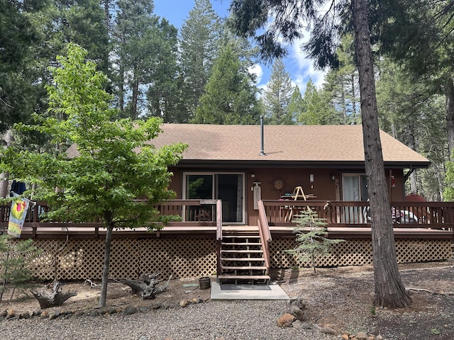 rear view of property featuring stairway, roof with shingles, and a deck