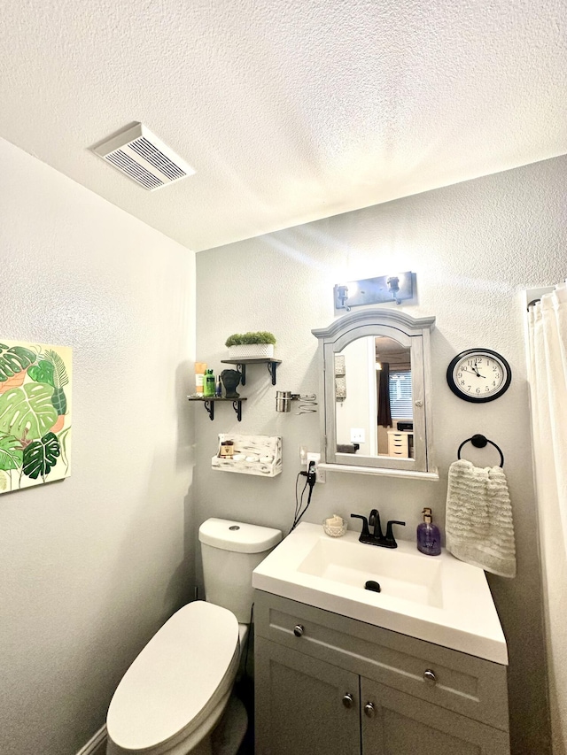 bathroom featuring toilet, a textured ceiling, visible vents, and vanity
