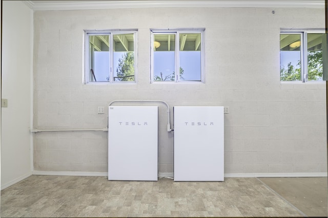 clothes washing area with concrete block wall, baseboards, and ornamental molding