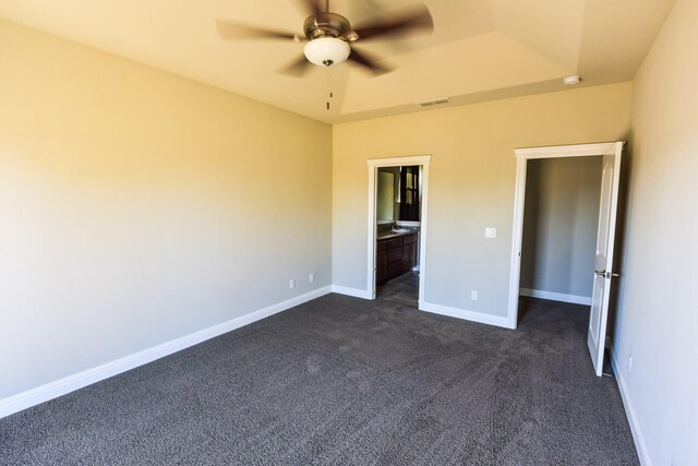 2876 Calaveras Ct, Redding, CA 96002 - unfurnished bedroom with dark colored carpet, a tray ceiling, baseboards, ensuite bathroom, and ceiling fan