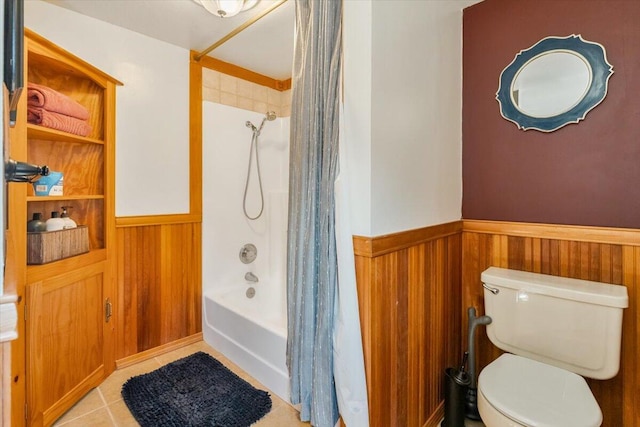 full bathroom featuring tile patterned flooring, toilet, a wainscoted wall, and shower / bath combo