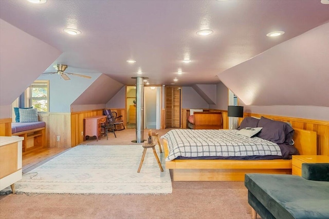 bedroom with lofted ceiling, wood walls, recessed lighting, and a wainscoted wall