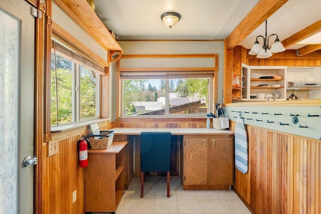 kitchen with light tile patterned floors, hanging light fixtures, brown cabinets, a chandelier, and tile counters