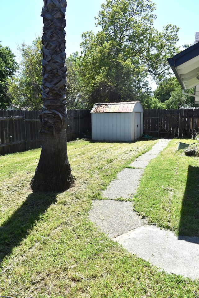 view of yard with a fenced backyard, a storage shed, and an outbuilding