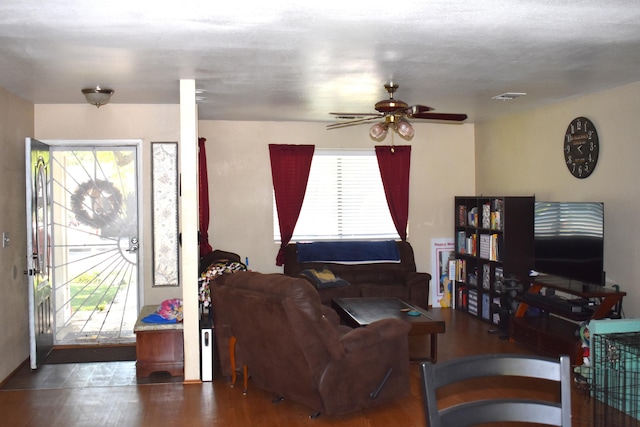 living area with a ceiling fan, a wealth of natural light, visible vents, and wood finished floors