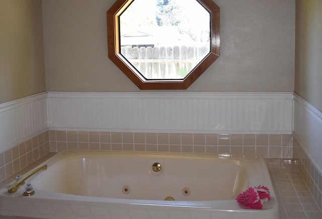 bathroom featuring a wainscoted wall and a jetted tub