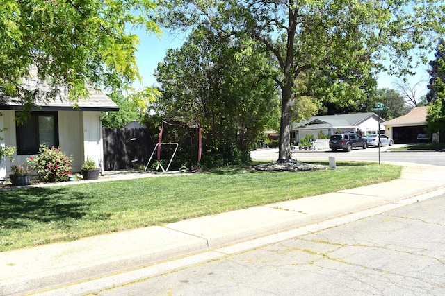 view of yard featuring concrete driveway and fence