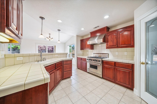 4217 Pendleton Ct, Shasta Lake, CA 96019 - kitchen featuring high end stove, reddish brown cabinets, a sink, wall chimney range hood, and lofted ceiling