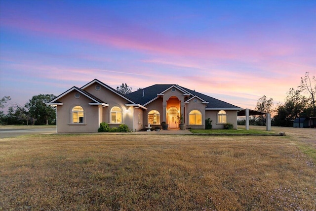 ranch-style home featuring a yard and stucco siding