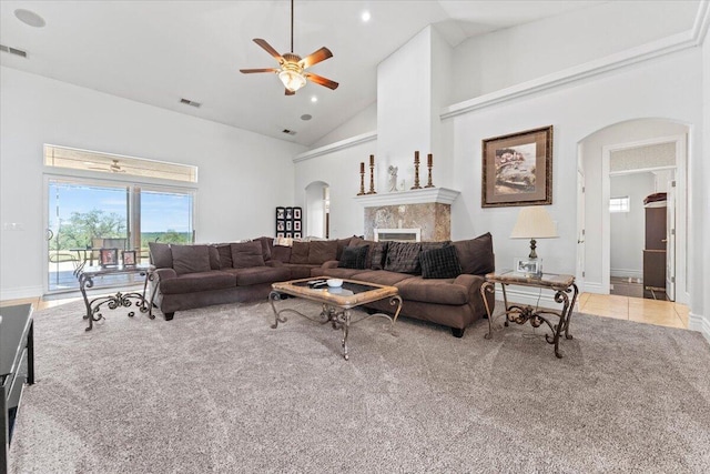carpeted living area with a ceiling fan, high vaulted ceiling, visible vents, baseboards, and arched walkways