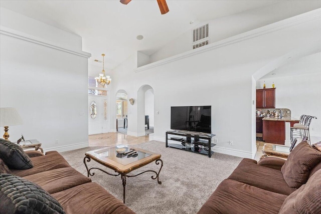living area with arched walkways, light carpet, visible vents, and ceiling fan with notable chandelier