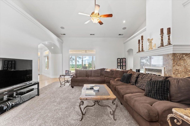 carpeted living room with high vaulted ceiling, arched walkways, a ceiling fan, and visible vents