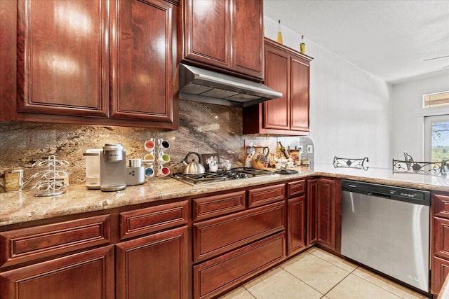 kitchen with tasteful backsplash, under cabinet range hood, light tile patterned floors, light stone countertops, and appliances with stainless steel finishes