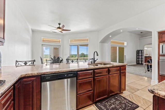 kitchen with light tile patterned floors, a ceiling fan, a sink, stainless steel appliances, and arched walkways