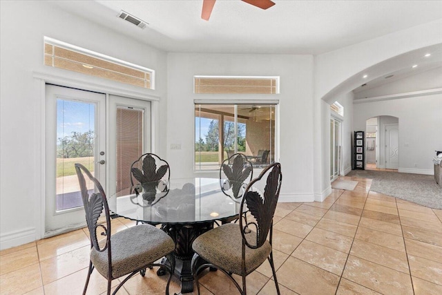 dining room with light tile patterned floors, arched walkways, a ceiling fan, and visible vents