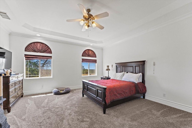 bedroom featuring a tray ceiling, ornamental molding, visible vents, and multiple windows