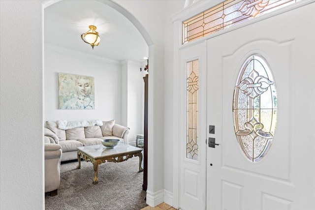 foyer entrance featuring carpet flooring, ornamental molding, and arched walkways