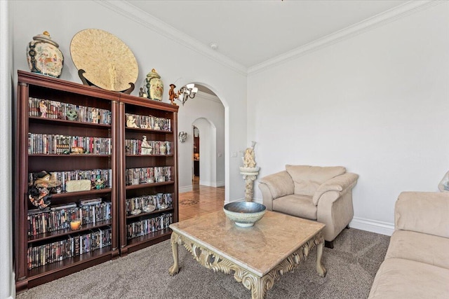 sitting room with crown molding, carpet, arched walkways, and baseboards
