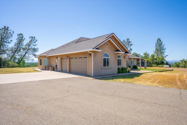 ranch-style home with a front lawn, stucco siding, driveway, and a garage