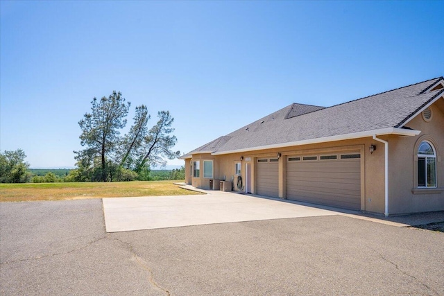 view of front of property featuring aphalt driveway, roof with shingles, a garage, and stucco siding