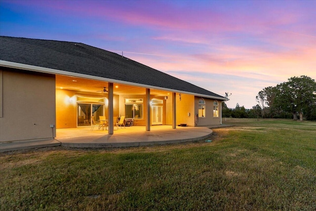 back of house with a yard, a patio, and stucco siding