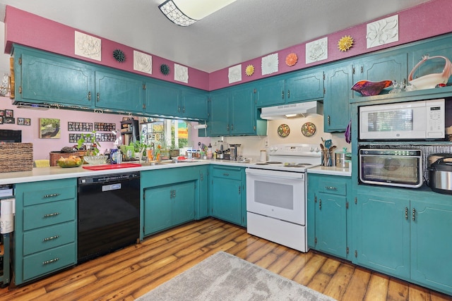 kitchen with under cabinet range hood, light countertops, light wood-type flooring, and white appliances