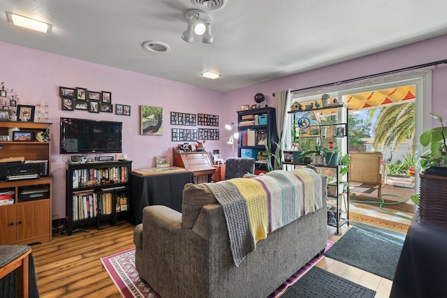 living area featuring visible vents and wood finished floors