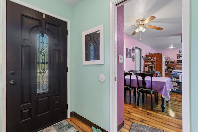 foyer entrance with a ceiling fan, baseboards, and wood finished floors