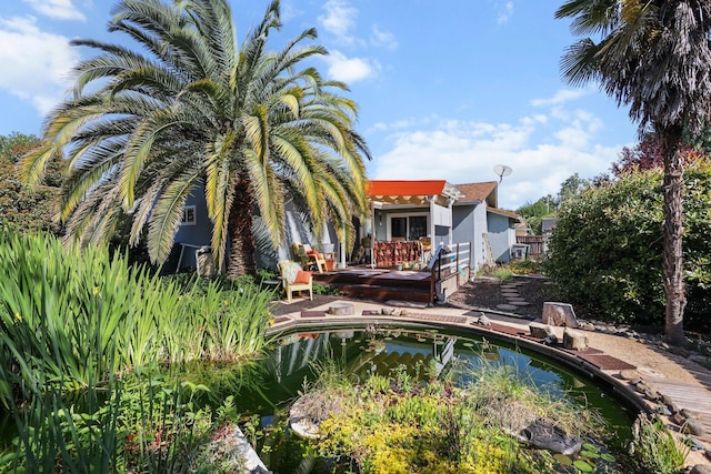 outdoor pool with a wooden deck, a small pond, and fence