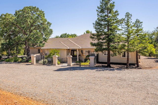 ranch-style house featuring a fenced front yard, stucco siding, and a gate