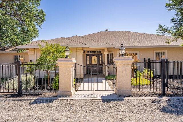 ranch-style house with a fenced front yard, stucco siding, and a gate