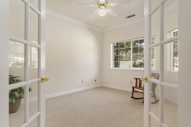 empty room featuring french doors, light colored carpet, visible vents, crown molding, and baseboards