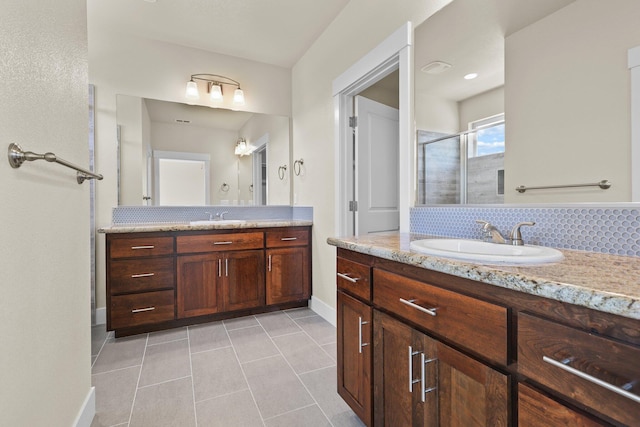 full bathroom featuring a stall shower, a sink, two vanities, baseboards, and tile patterned flooring