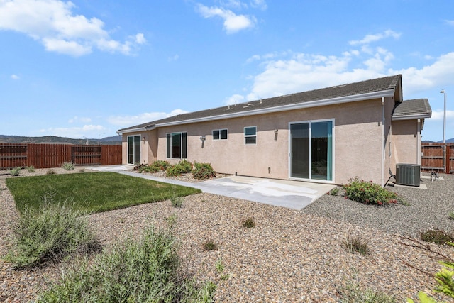 rear view of house with stucco siding, a patio area, and a fenced backyard