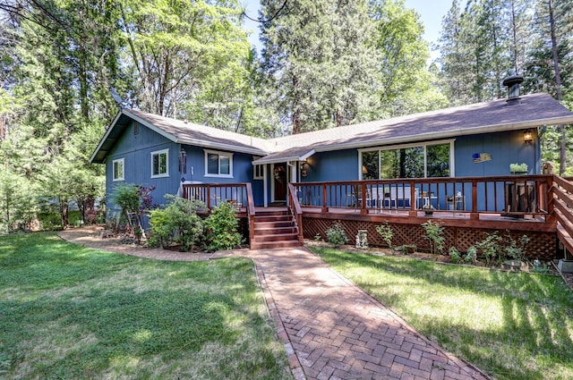 rear view of house with a wooden deck, a lawn, and a shingled roof