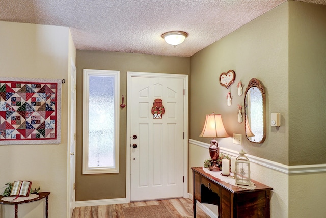 entrance foyer featuring light wood-style floors, a textured ceiling, and baseboards