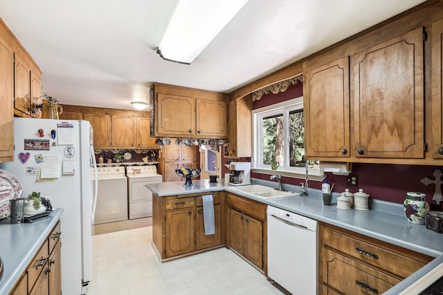 kitchen featuring white appliances, washer and clothes dryer, a sink, and brown cabinets