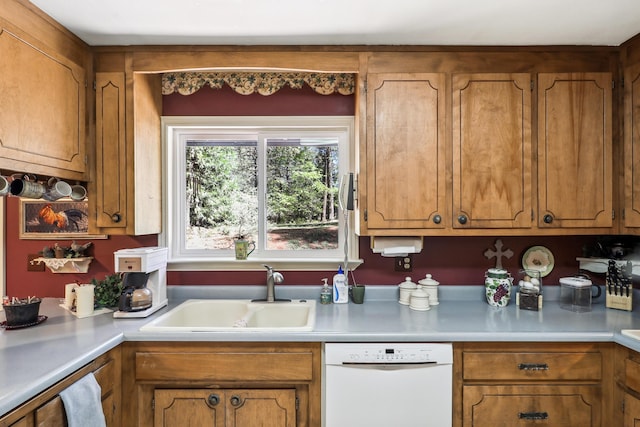 kitchen featuring white dishwasher, a sink, and light countertops