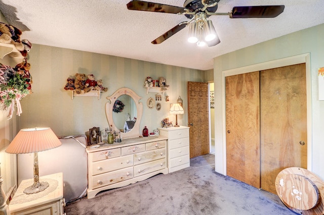bedroom with carpet floors, a closet, a textured ceiling, ceiling fan, and wallpapered walls