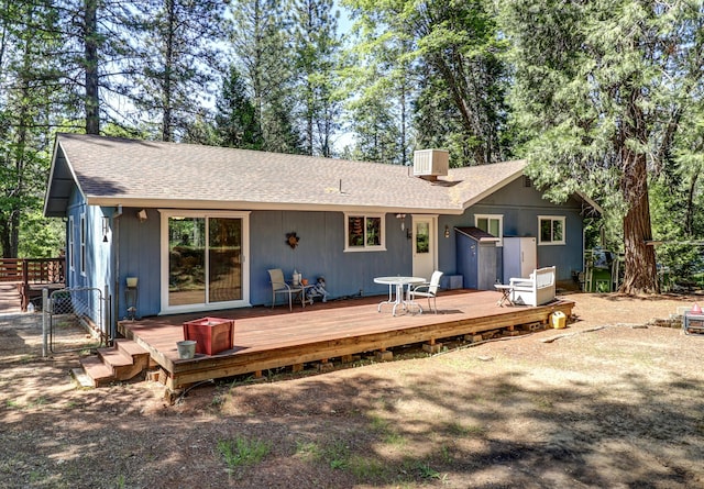 rear view of house with roof with shingles, a chimney, a deck, and fence